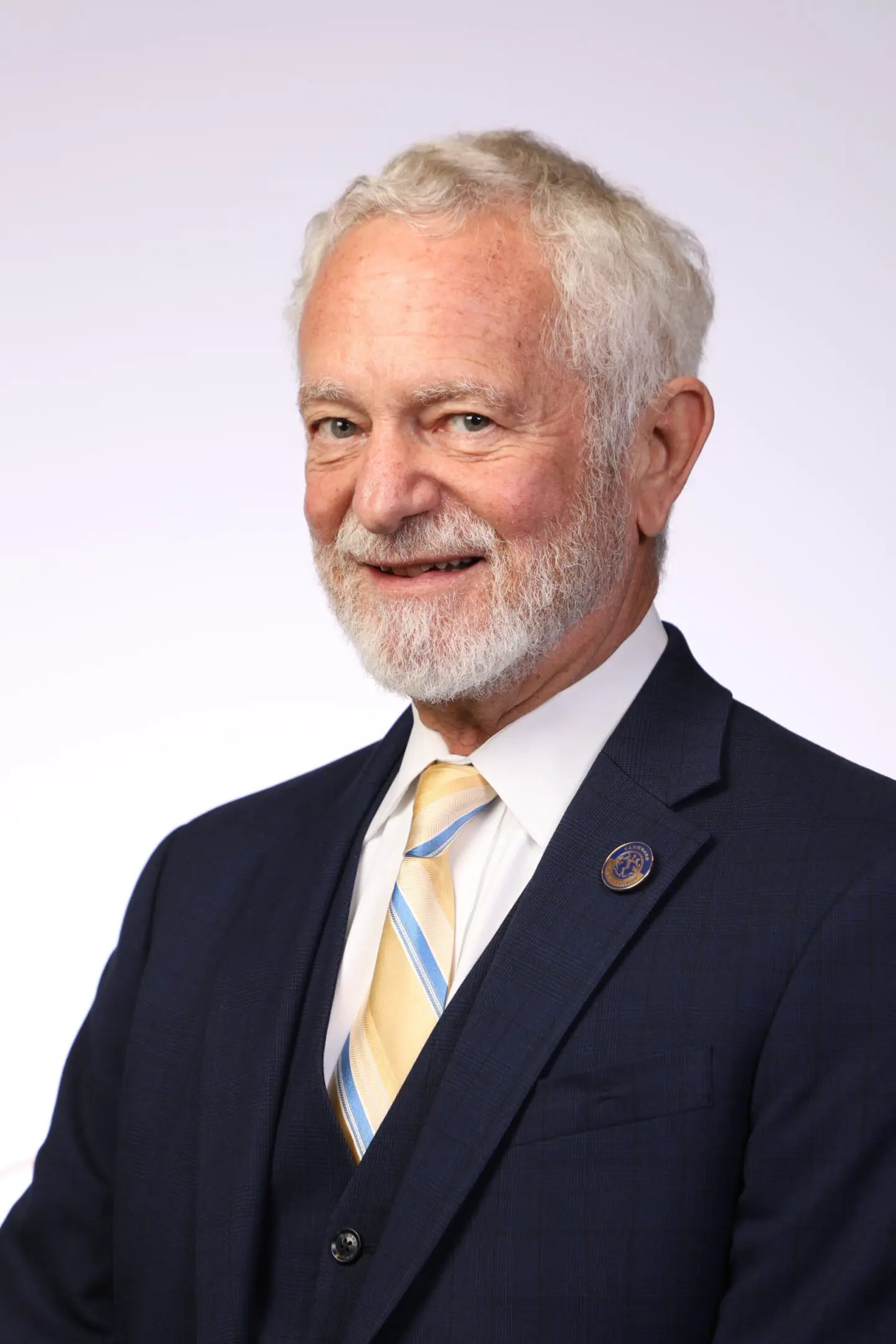 A man with white hair and beard wearing a suit.