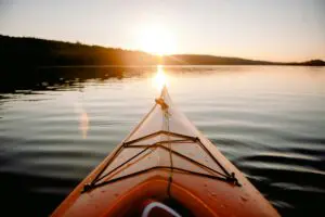 Kayak on calm lake at sunset.