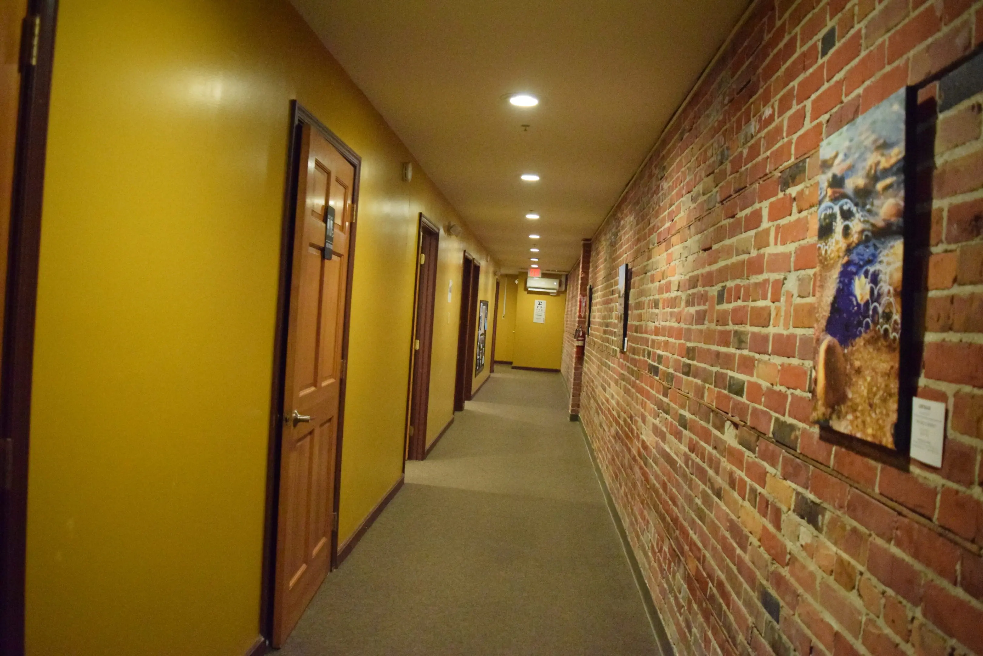 Brick hallway with doors and framed art.